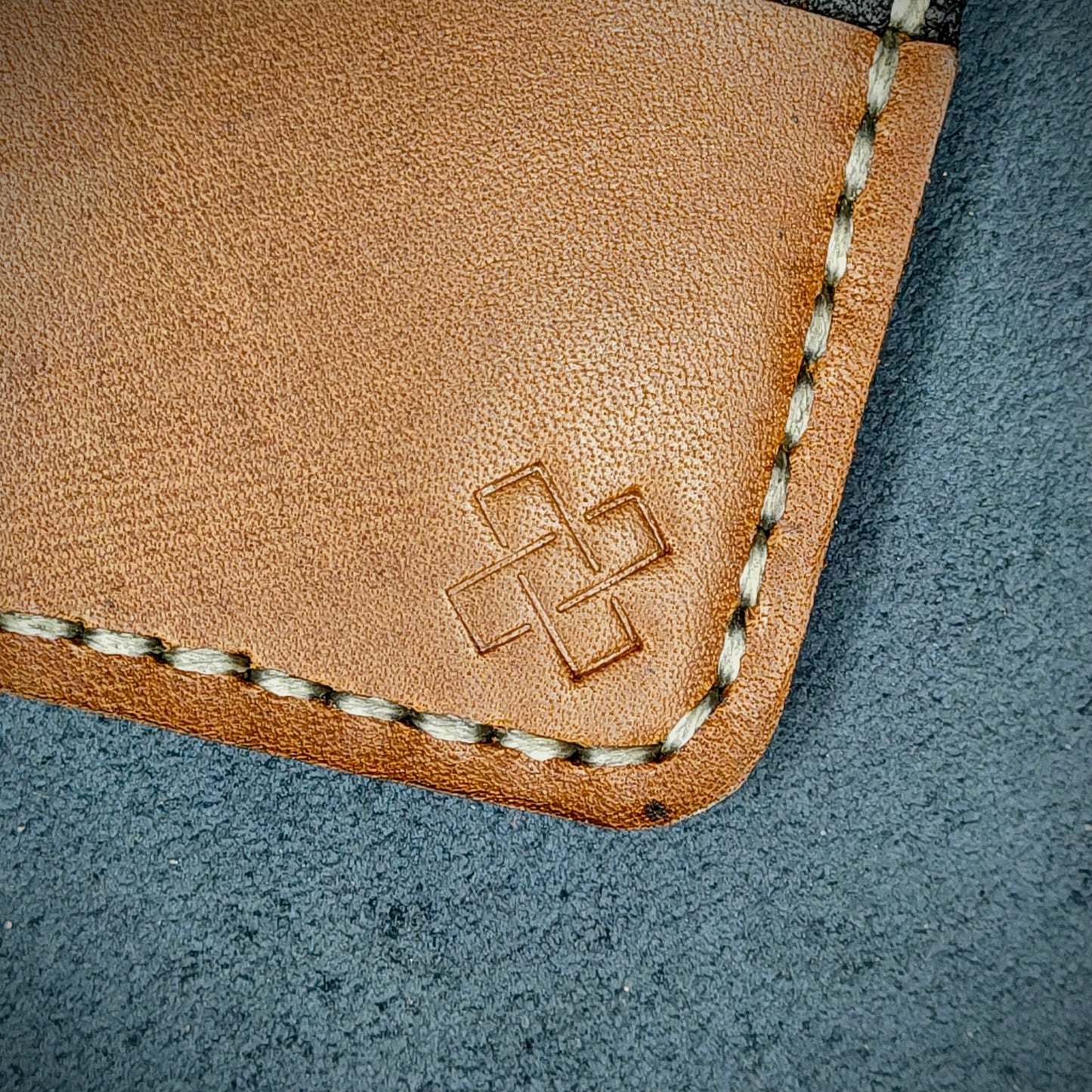 Back view close-up of the design logo emboss on the back of The Houdini card holder– focusing on the fine grain detail of ethically sourced Brown full-grain leather and meticulous saddle stitching. Showcases the subtle artistry and understated luxury of Novelty Atelier’s craftsmanship.