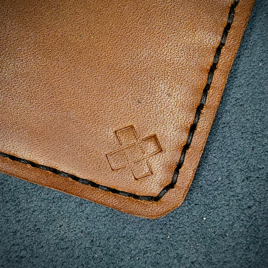 Back view close-up of the design logo emboss on the back of The Houdini card holder– focusing on the fine grain detail of ethically sourced Brown full-grain leather and meticulous saddle stitching. Showcases the subtle artistry and understated luxury of Novelty Atelier’s craftsmanship.