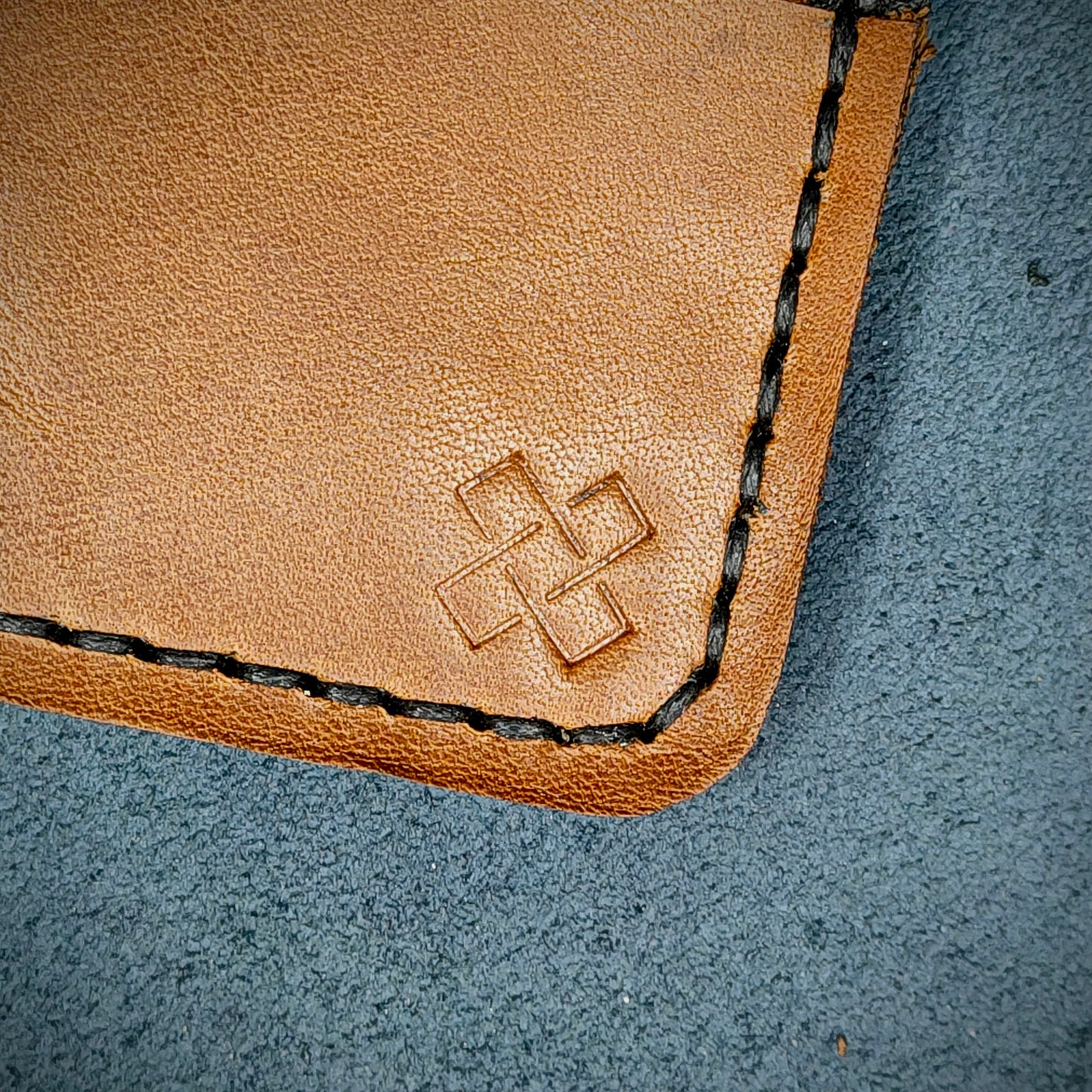 Back view close-up of the design logo emboss on the back of The Houdini card holder horizontal configuration – focusing on the fine grain detail of ethically sourced Brown full-grain leather and meticulous saddle stitching. Showcases the subtle artistry and understated luxury of Novelty Atelier’s craftsmanship.