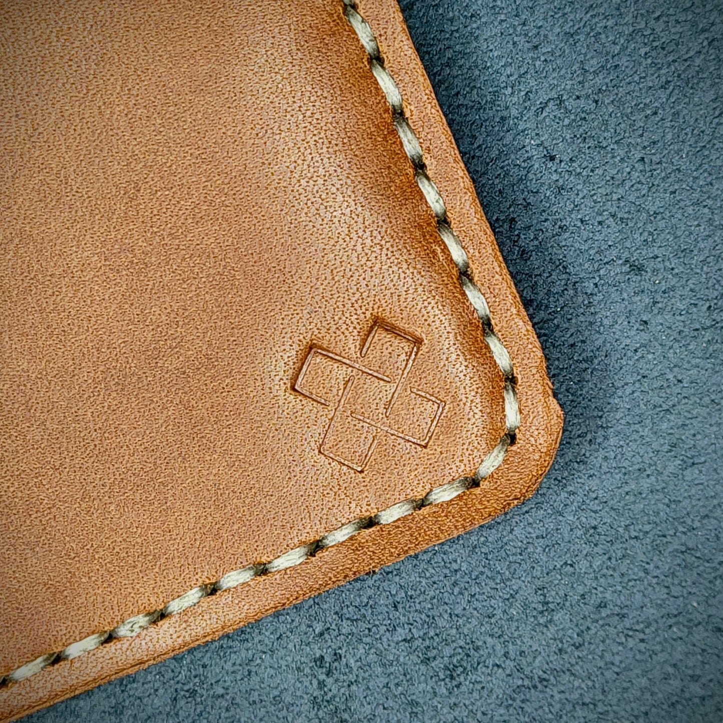 Back view close-up of the design logo emboss on the back of The Houdini card holder in vertical configuration – focusing on the fine grain detail of ethically sourced Brown full-grain leather and meticulous saddle stitching. Showcases the subtle artistry and understated luxury of Novelty Atelier’s craftsmanship.