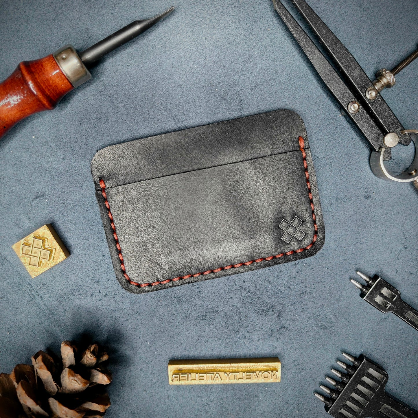 Back view of The Houdini minimalist leather card holder in horizontal configuration by Novelty Atelier – features a clean, functional layout with the design logo subtly stamped into black full-grain leather. Accented with red saddle stitching for a timeless aesthetic.
