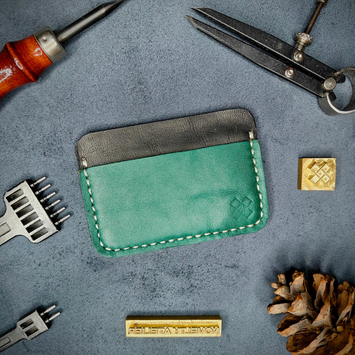 Back view of The Houdini minimalist leather card holder in horizontal configuration by Novelty Atelier – features a clean, functional layout with the design logo subtly stamped into green full-grain leather. Accented with off white saddle stitching for a timeless aesthetic.