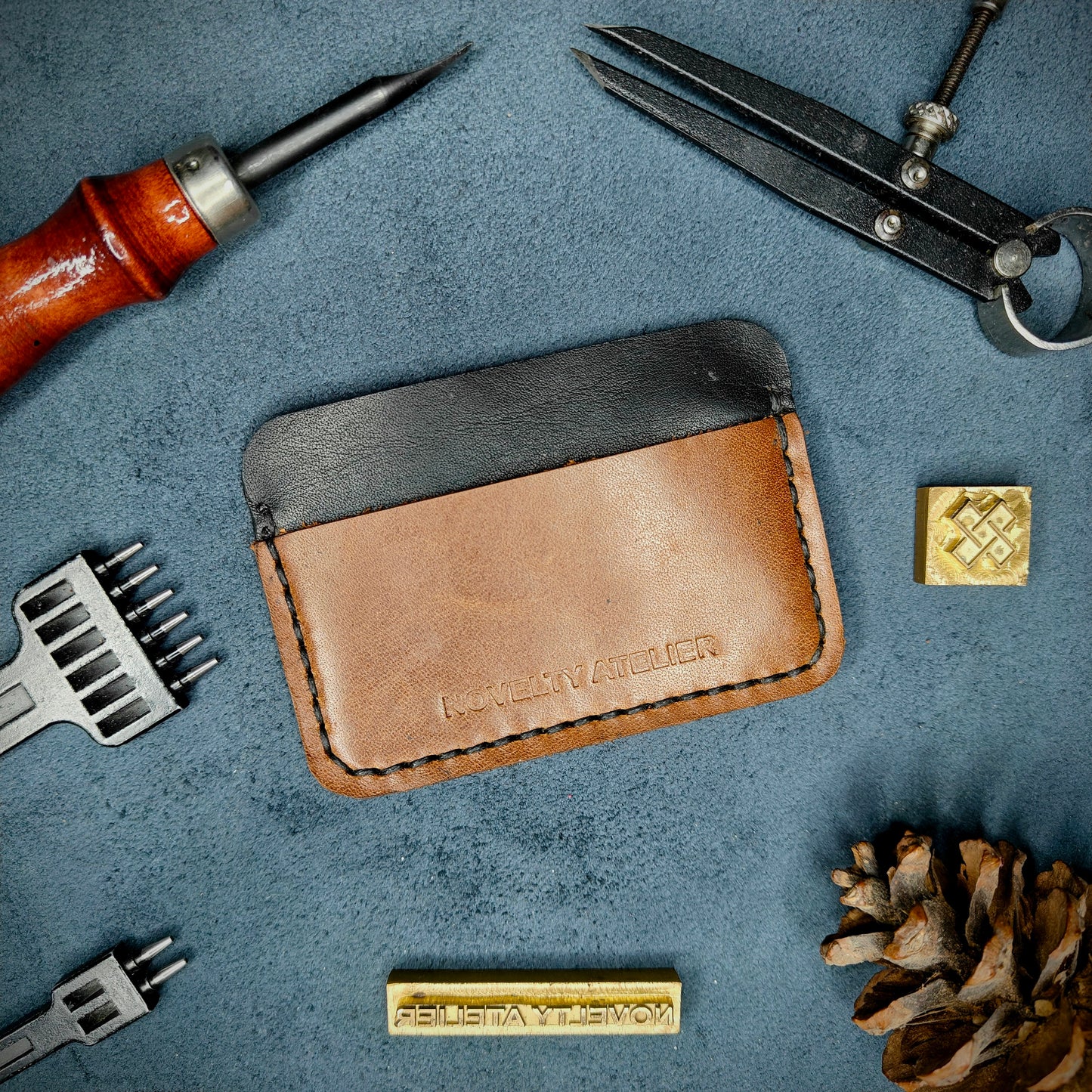 Front view of The Houdini minimalist card holder in horizontal configuration by Novelty Atelier – handcrafted from Black and Brown ethically sourced full-grain leather with crisp Black saddle stitching. Features the “Novelty Atelier” brand name cleanly embossed on the front. Perfectly balanced minimalist wallet design tailored for modern EDC enthusiasts who value craftsmanship and brand integrity.