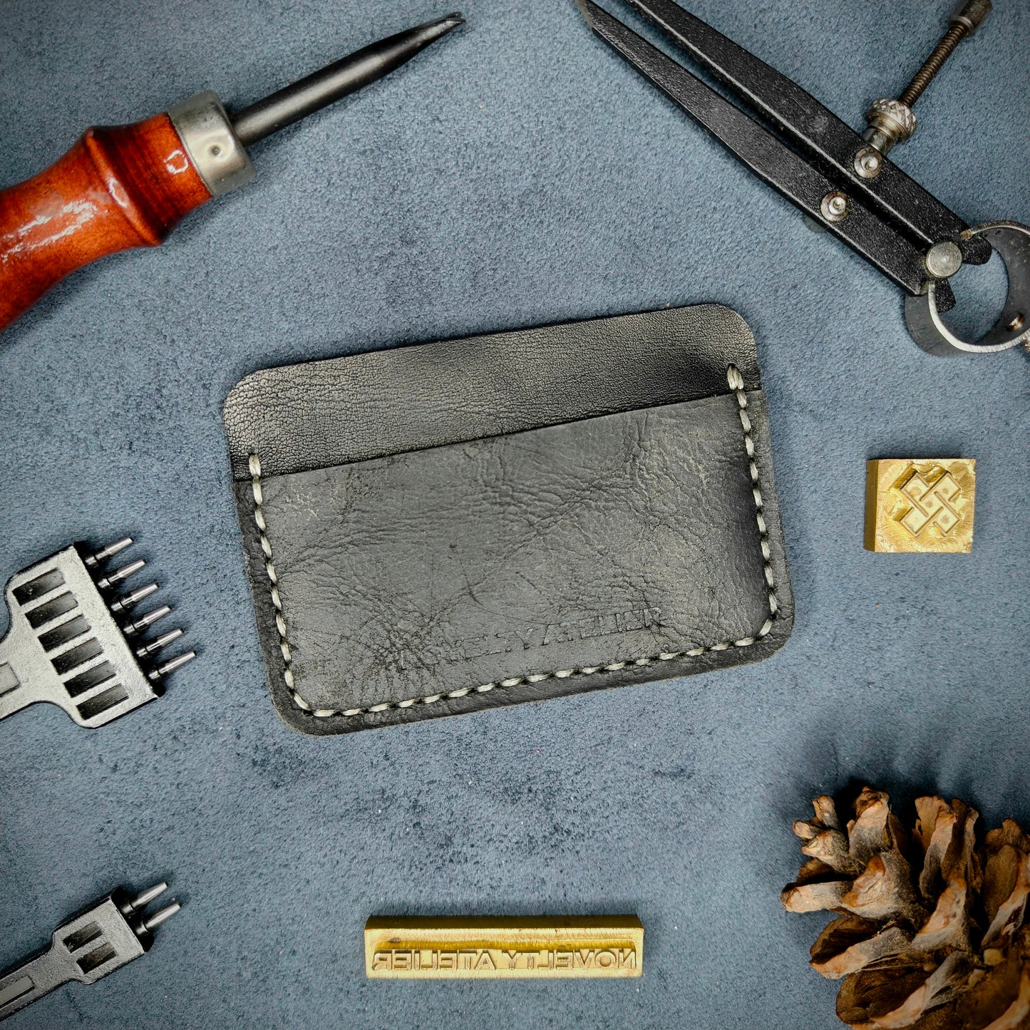 Front view of The Houdini minimalist card holder in horizontal configuration by Novelty Atelier – handcrafted from Black ethically sourced full-grain leather with contrasting off-white saddle stitching. Features the “Novelty Atelier” brand name cleanly embossed on the front. Perfectly balanced minimalist wallet design tailored for modern EDC enthusiasts who value craftsmanship and brand integrity.