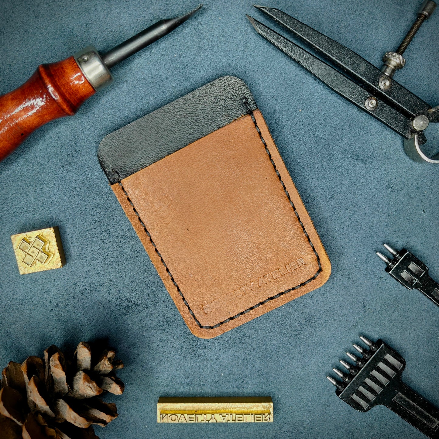 Front view of The Houdini minimalist card holder in vertical configuration by Novelty Atelier – handcrafted from Black and Tann ethically sourced full-grain leather with contrasting Black saddle stitching. Features the “Novelty Atelier” brand name cleanly embossed on the front. Perfectly balanced minimalist wallet design tailored for modern EDC enthusiasts who value craftsmanship and brand integrity.