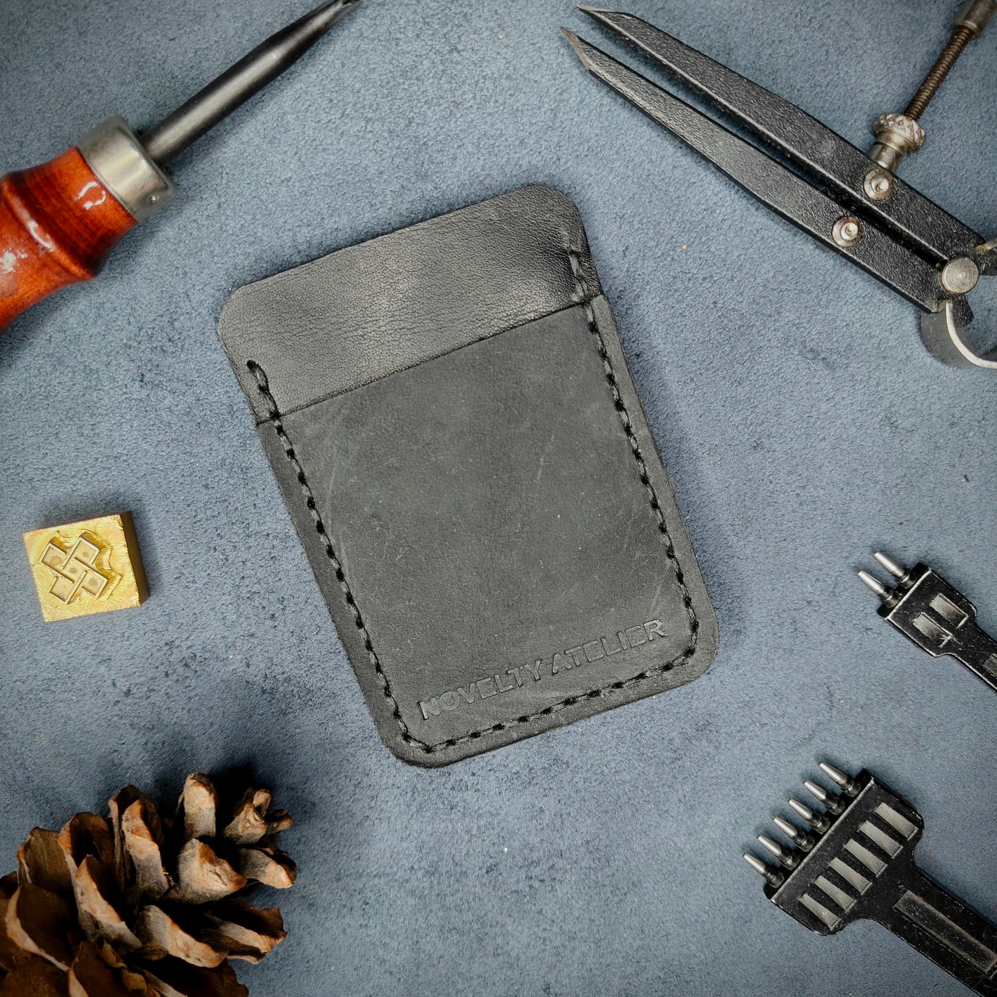 Front view of The Houdini minimalist card holder in vertical configuration by Novelty Atelier – handcrafted from Black ethically sourced full-grain leather with contrasting Black saddle stitching. Features the “Novelty Atelier” brand name cleanly embossed on the front. Perfectly balanced minimalist wallet design tailored for modern EDC enthusiasts who value craftsmanship and brand integrity.