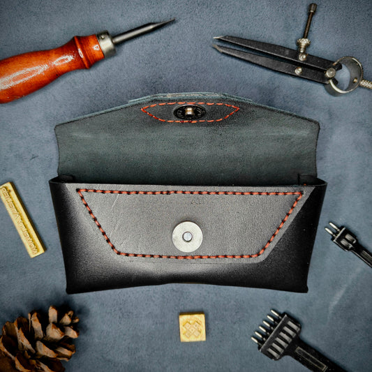 The Hustler - Sunglass case black full grain leather - open with magnetic snap Detailed picture showing the brand name logo with tools surrounding for aesthetics