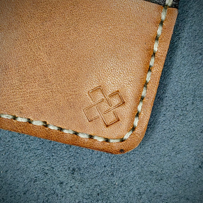 Back view close-up of the design logo emboss on the back of The Houdini card holder– focusing on the fine grain detail of ethically sourced Brown full-grain leather and meticulous saddle stitching. Showcases the subtle artistry and understated luxury of Novelty Atelier’s craftsmanship.
