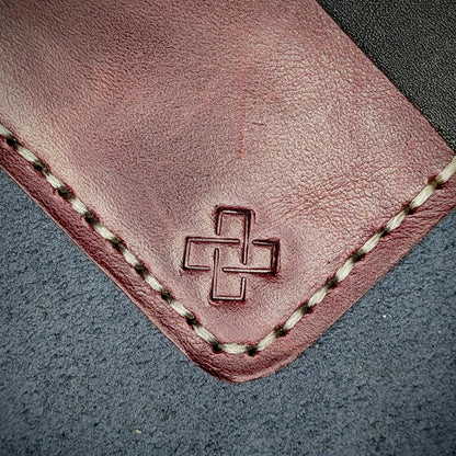 Back view close-up of the design logo emboss on the back of The Houdini card holder in horizontal configuration– focusing on the fine grain detail of ethically sourced Purple full-grain leather and meticulous off-white saddle stitching. Showcases the subtle artistry and understated luxury of Novelty Atelier’s craftsmanship.
