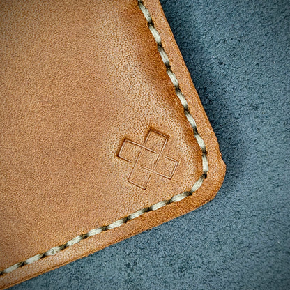 Back view close-up of the design logo emboss on the back of The Houdini card holder in vertical configuration – focusing on the fine grain detail of ethically sourced Brown full-grain leather and meticulous saddle stitching. Showcases the subtle artistry and understated luxury of Novelty Atelier’s craftsmanship.
