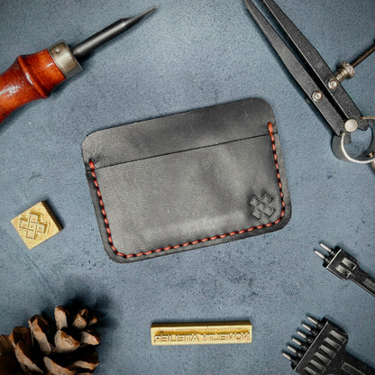 Back view of The Houdini minimalist leather card holder in horizontal configuration by Novelty Atelier – features a clean, functional layout with the design logo subtly stamped into black full-grain leather. Accented with red saddle stitching for a timeless aesthetic.
