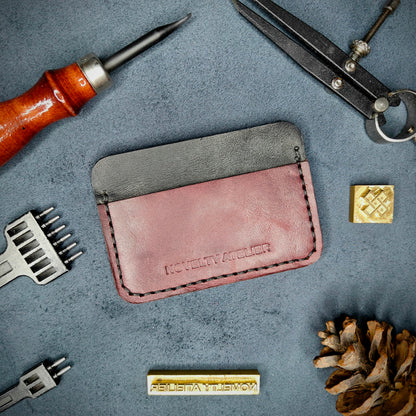 Front view of The Houdini minimalist card holder in horizontal configuration by Novelty Atelier – handcrafted from Black and Purple ethically sourced full-grain leather with crisp Black saddle stitching. Features the “Novelty Atelier” brand name cleanly embossed on the front. Perfectly balanced minimalist wallet design tailored for modern EDC enthusiasts who value craftsmanship and brand integrity.

