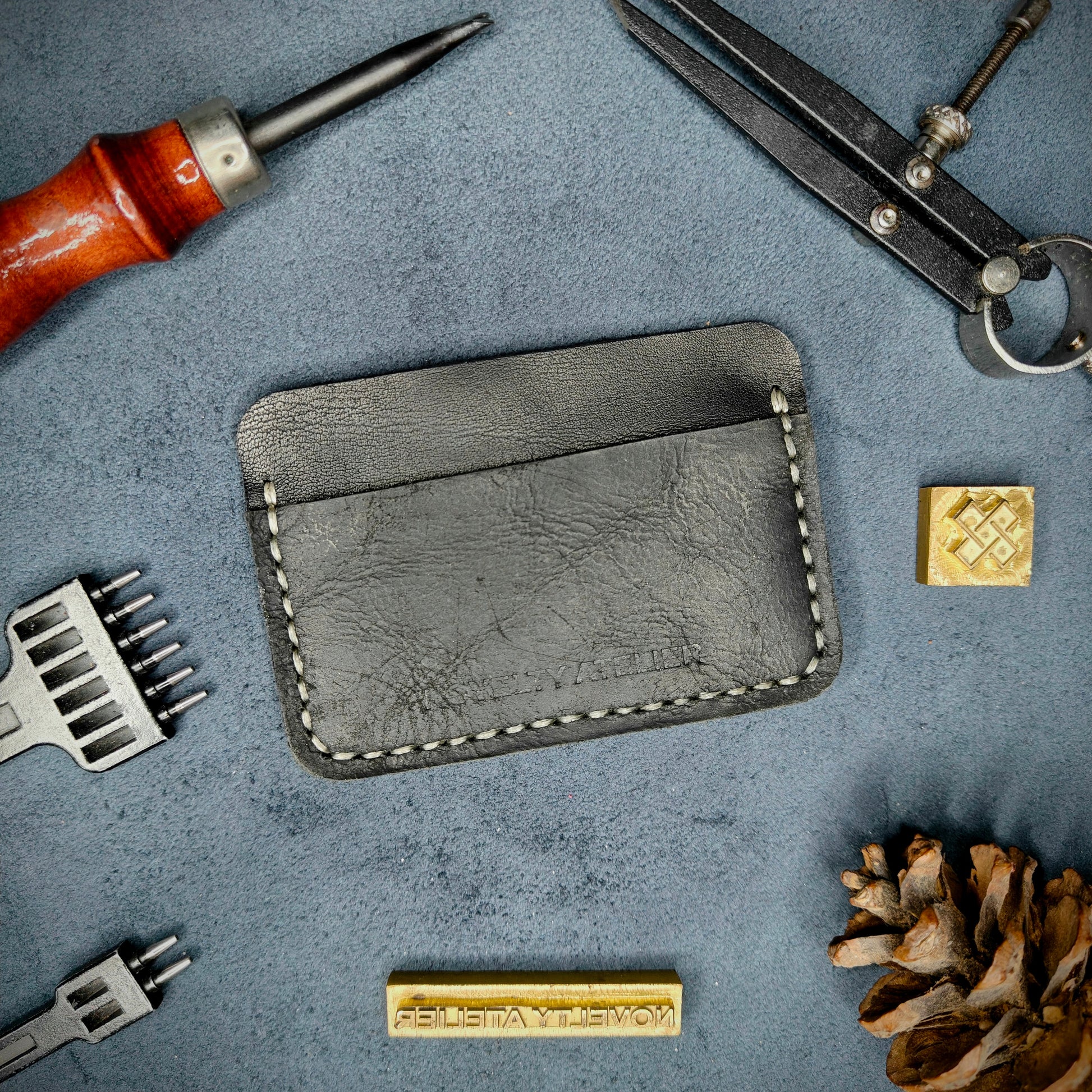 Front view of The Houdini minimalist card holder in horizontal configuration by Novelty Atelier – handcrafted from Black ethically sourced full-grain leather with contrasting off-white saddle stitching. Features the “Novelty Atelier” brand name cleanly embossed on the front. Perfectly balanced minimalist wallet design tailored for modern EDC enthusiasts who value craftsmanship and brand integrity.
