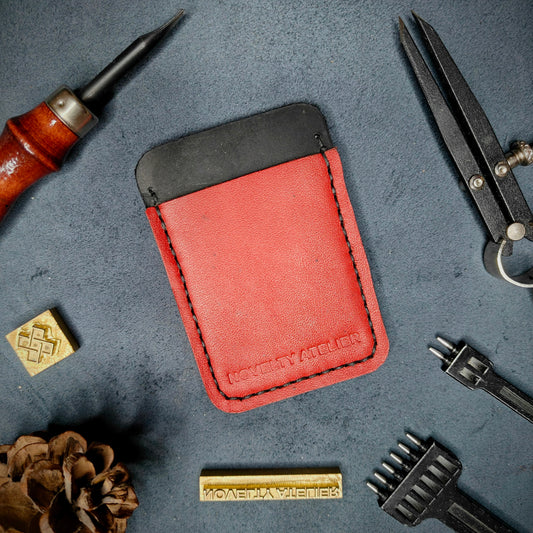 Front view of The Houdini minimalist card holder in vertical configuration by Novelty Atelier – handcrafted from Black and Red ethically sourced full-grain leather with contrasting Black saddle stitching. Features the “Novelty Atelier” brand name cleanly embossed on the front. Perfectly balanced minimalist wallet design tailored for modern EDC enthusiasts who value craftsmanship and brand integrity.
