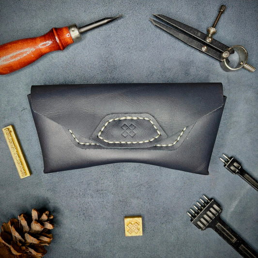 The Hustler - Sunglass case Navy blue full grain leather - closed with magnetic snap Detailed picture showing the logo with tools surrounding for aesthetics