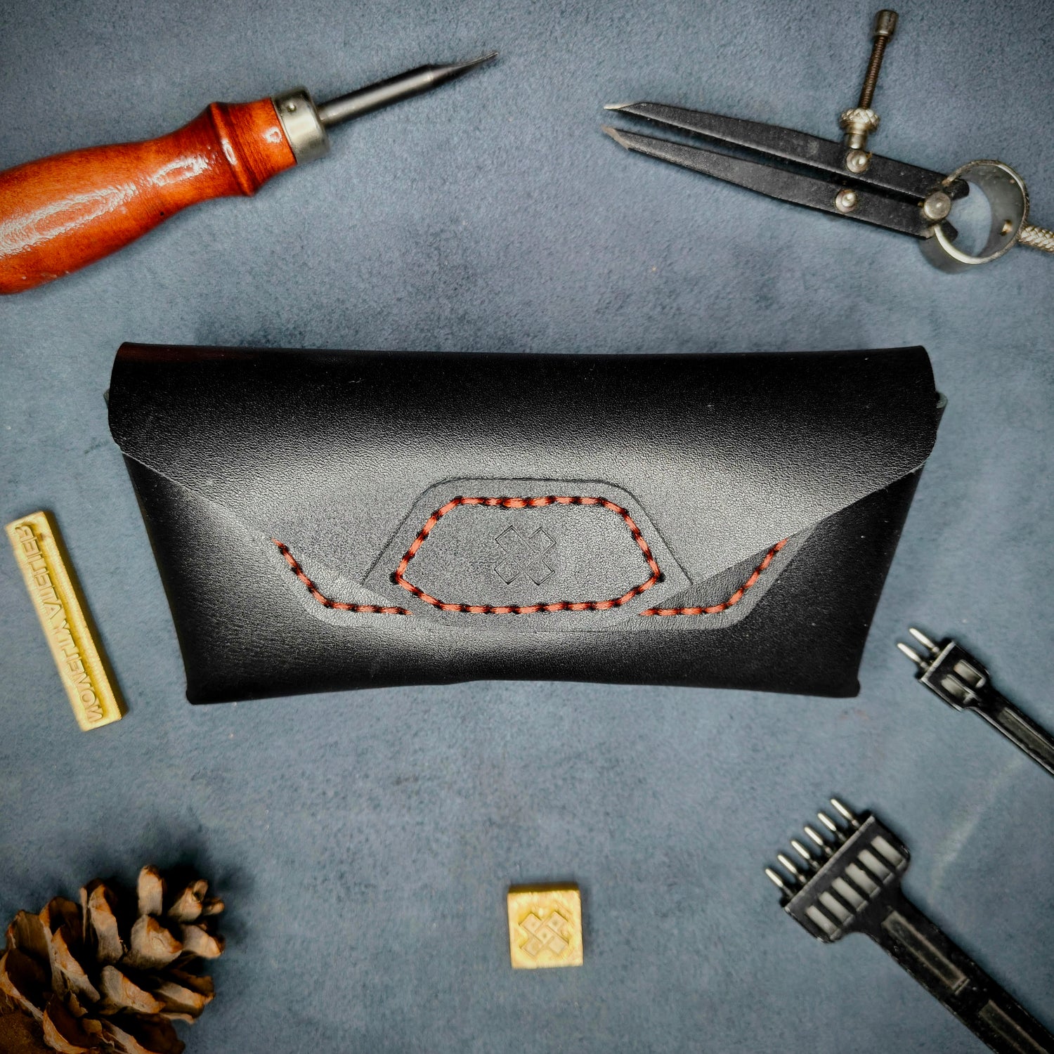The Hustler - Sunglass case black full grain leather - closed with magnetic snap Detailed picture showing the logo with tools surrounding for aesthetics